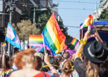 Picture of a crowd of people holding and raising rainbow flags, symbol of the homosexual struggle, during a gay demonstration. The rainbow flag, commonly known as the gay pride flag or LGBT pride flag, is a symbol of lesbian, gay, bisexual and transgender (LGBT) pride and LGBT social movements. Other older uses of rainbow flags include a symbol of peace.