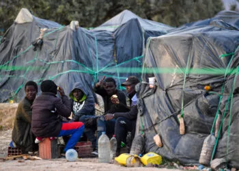 Migrants from sub-Saharan Africa sit next to makeshift shelters at a camp al-Amra on the outskirts of the Tunisian port city of Sfax on April 23, 2024. After President Kais Saied said in a speech last year that "hordes of illegal migrants" posed a demographic threat to Tunisia, anti-migrant violence broke out and hundreds of sub-Saharan Africans were kicked out of their jobs and homes. (Photo by Fethi Belaid / AFP)