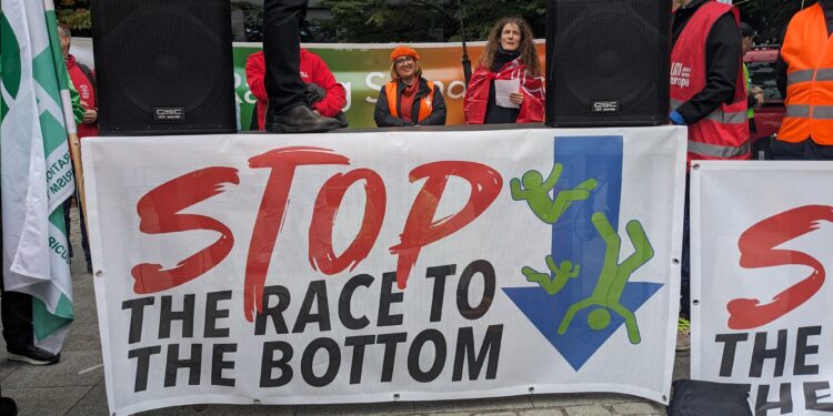 Uno striscione alla manifestazione in piazza Jean Rey che recita "Stop alla corsa al ribasso" (foto: Fabiana Luca)