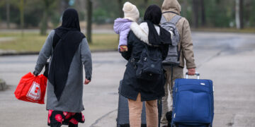 13 March 2025, Brandenburg, Eisenhüttenstadt: Migrants leave the premises of Brandenburg's Central Immigration Office (ZABH) with luggage. (Photo by PATRICK PLEUL / dpa Picture-Alliance via AFP)