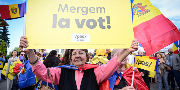 A supporter of Action and Solidarity Party PAS hold a pancarte reading "We go to vote"!  during a rally and march in Chisinau September 26, 2025 ahead of parliamentary elections.(Photo by Daniel MIHAILESCU / AFP)