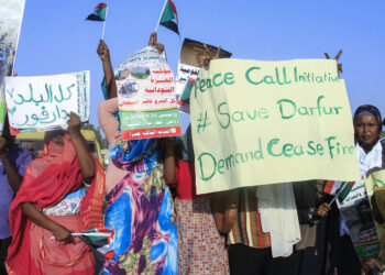 People lift national flags and placards during a rally called for by Sudan's Popular Front for Liberation and Justice in Port Sudan on April 24, 2025, to denounce the siege imposed by the paramilitary Rapid Support Forces (RSF) on El-Fasher city and express support for its residents. (Photo by AFP)