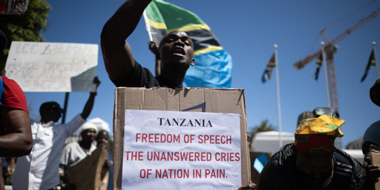 A protester holds a placard during a picket where about 50 Tanzanians living in Cape Town protested against the recent actions by the Tanzanian government during their presidential election, outside the South African Parliament in Cape Town on November 5, 2025. (Photo by RODGER BOSCH / AFP)