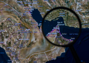 The Strait of Hormuz is pictured through a magnifying glass in this photo illustration, as the Iran conflict continues to restrict shipping through the key oil transit route, through which around 20% of global crude supply passes, fueling volatility in energy markets. Taken in Brussels, Belgium, on 6 April 2026. (Jonathan Raa / Sipa USA)