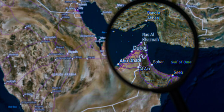 The Strait of Hormuz is pictured through a magnifying glass in this photo illustration, as the Iran conflict continues to restrict shipping through the key oil transit route, through which around 20% of global crude supply passes, fueling volatility in energy markets. Taken in Brussels, Belgium, on 6 April 2026. (Jonathan Raa / Sipa USA)